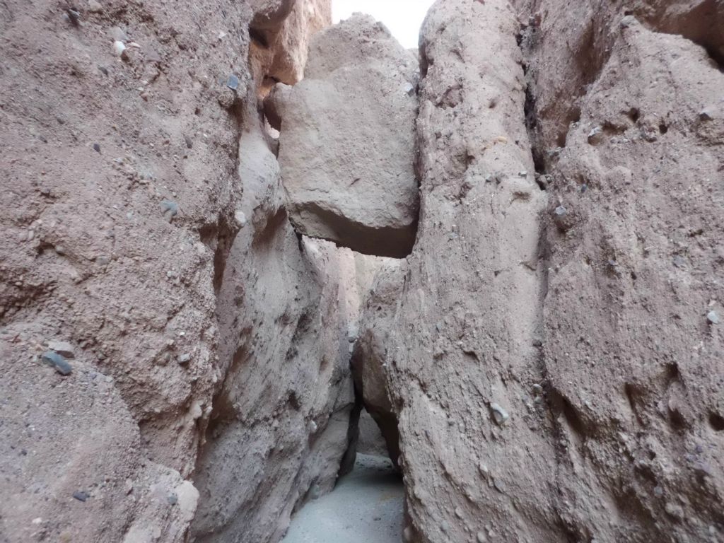 In this picture, you can see two fun obstacles we encountered in the narrows of Room Canyon.  Up above, a large boulder has gotten wedged between the walls.  A little further (and lower) is a passage that has to be crawled through to continue: