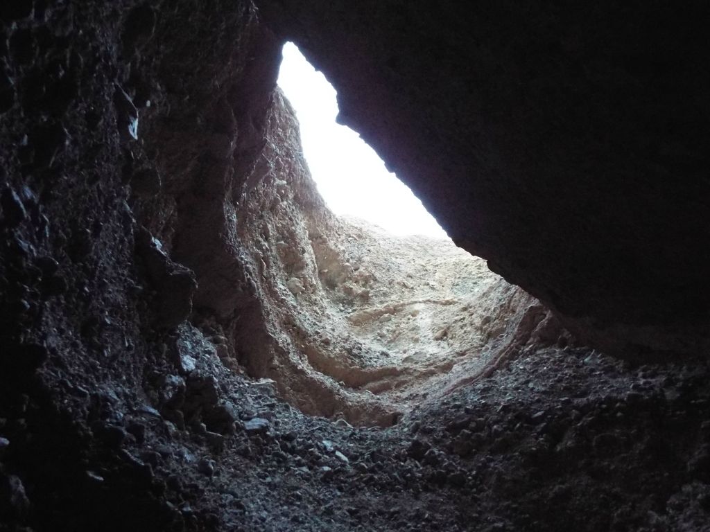 Looking up at the light high above the slot being partially blocked by a wedged boulder: