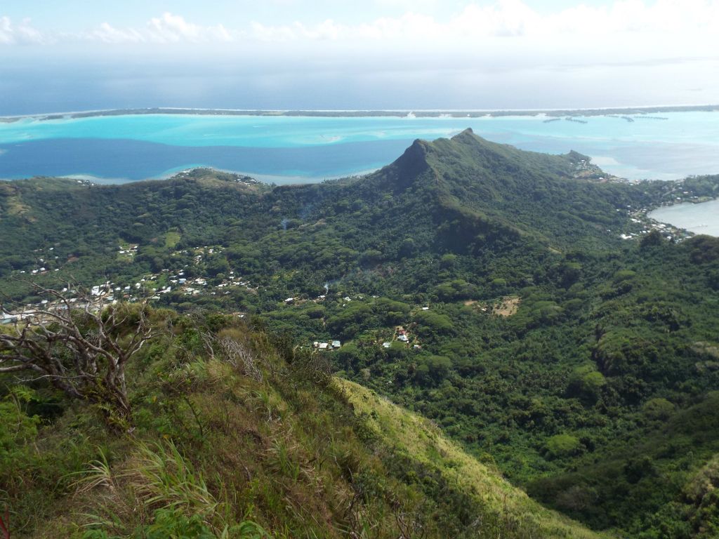 To the northeast, a view of Faanui village.  To the right of the village, a road heads into the interior toward the low ridge of Mount Mataihua but stops before crossing it: