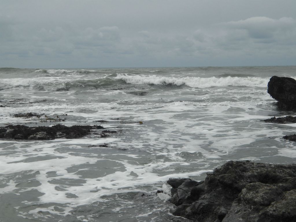 Two views looking out toward the ocean and incoming waves on a cloudy day: