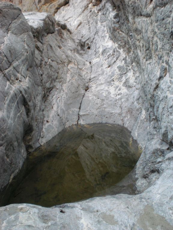 A pothole filled with water at the bottom of a polished slide: