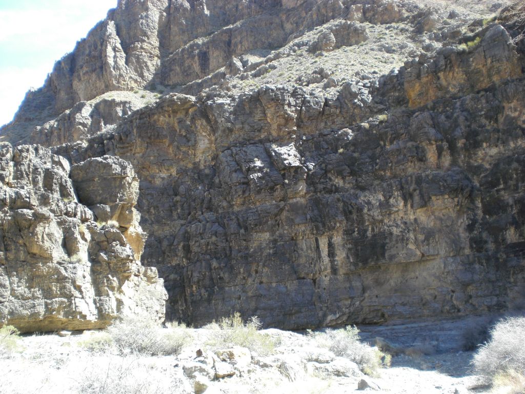 Rock walls with jagged edges and hillsides above: