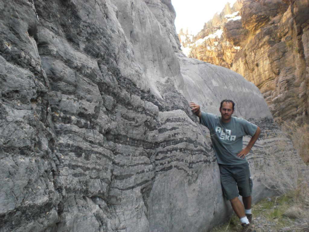 Steve getting a picture by the canyon wall with black bands: