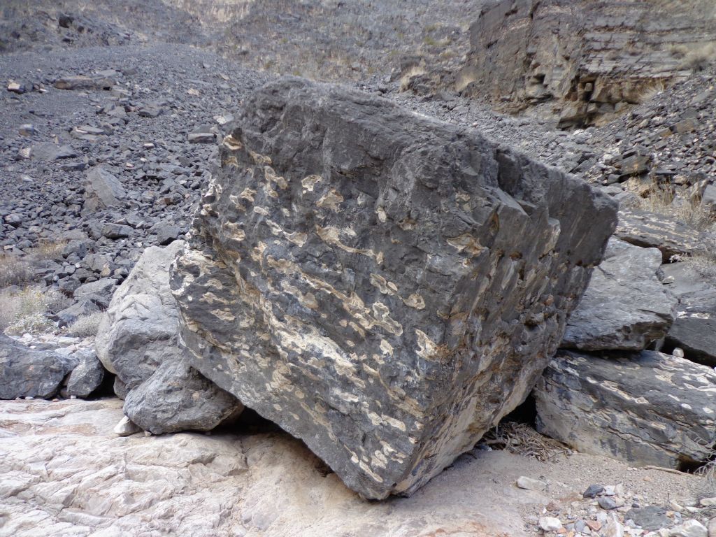 A large boulder shaped like a square block somehow rolled to the front of this gravel slide:
