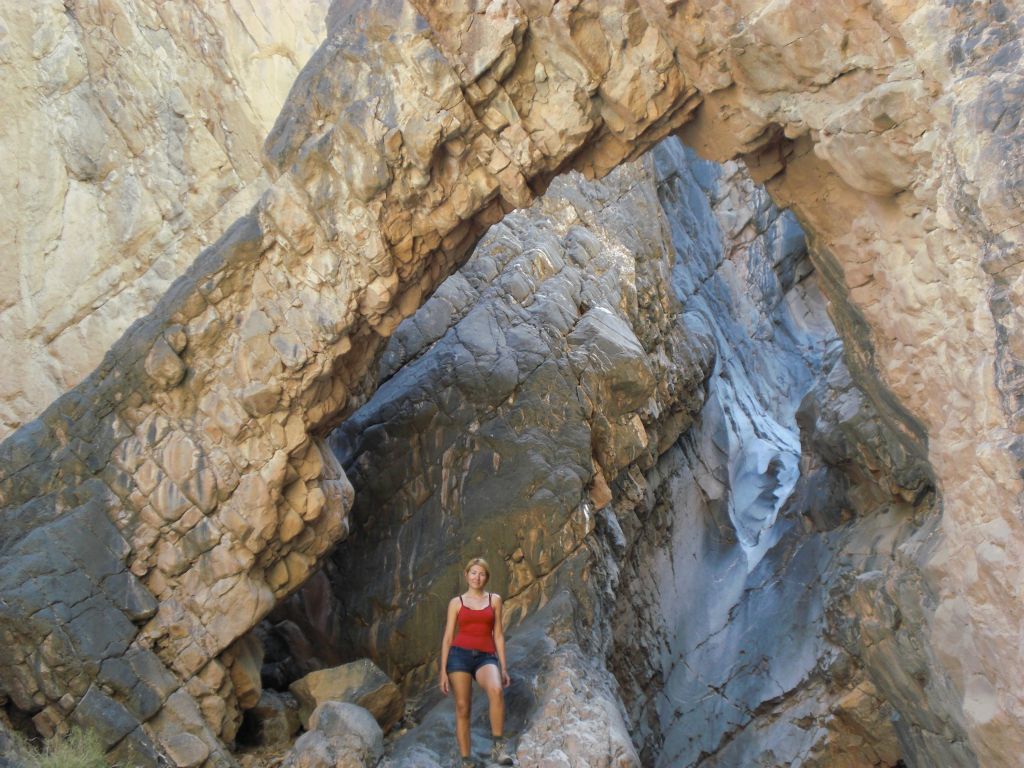 A picture of Daria underneath Hidden Bridge with the major dry fall behind her:
