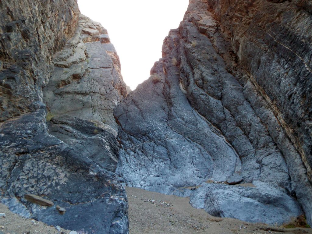 The rock takes strange angles as tilted layers rise up from the wash: