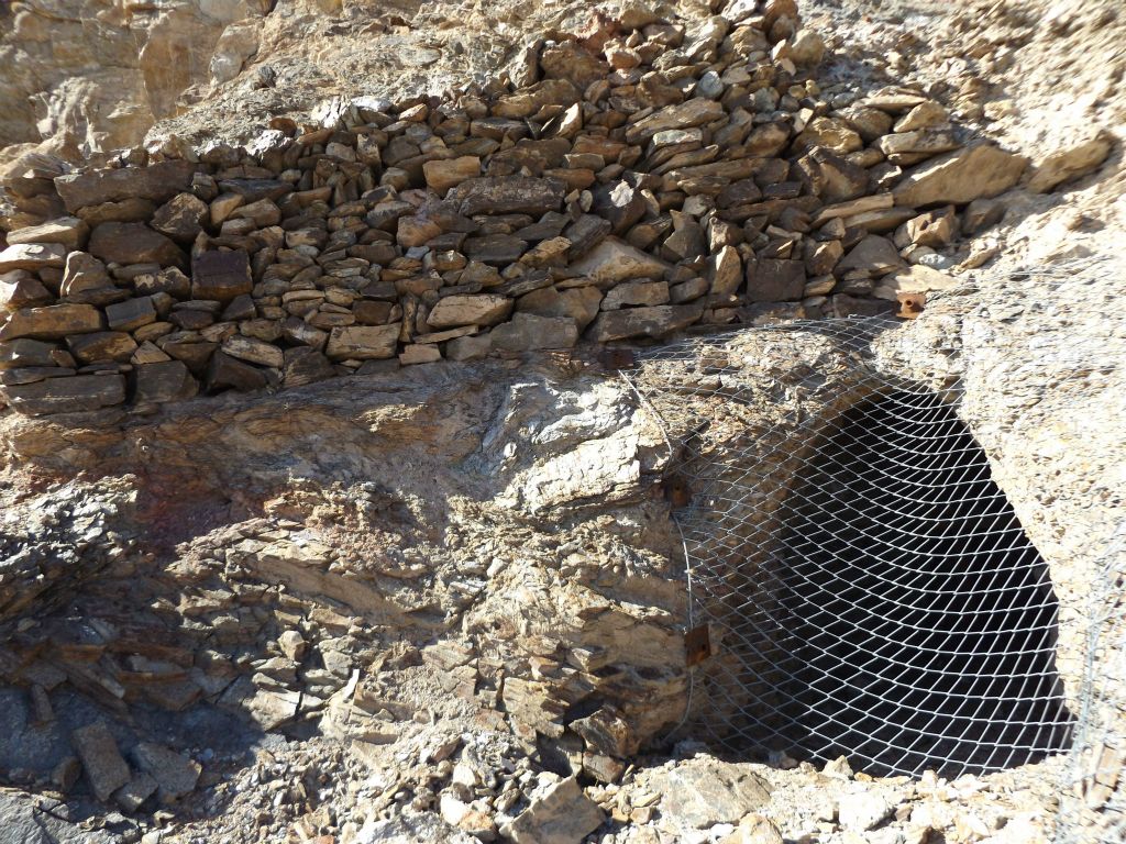 Notice the extensive rock wall which was built up by miners above this closed-off mining tunnel: