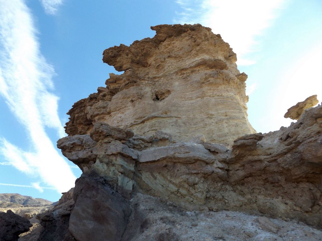 A large eroded formation rising above the small canyon wash: