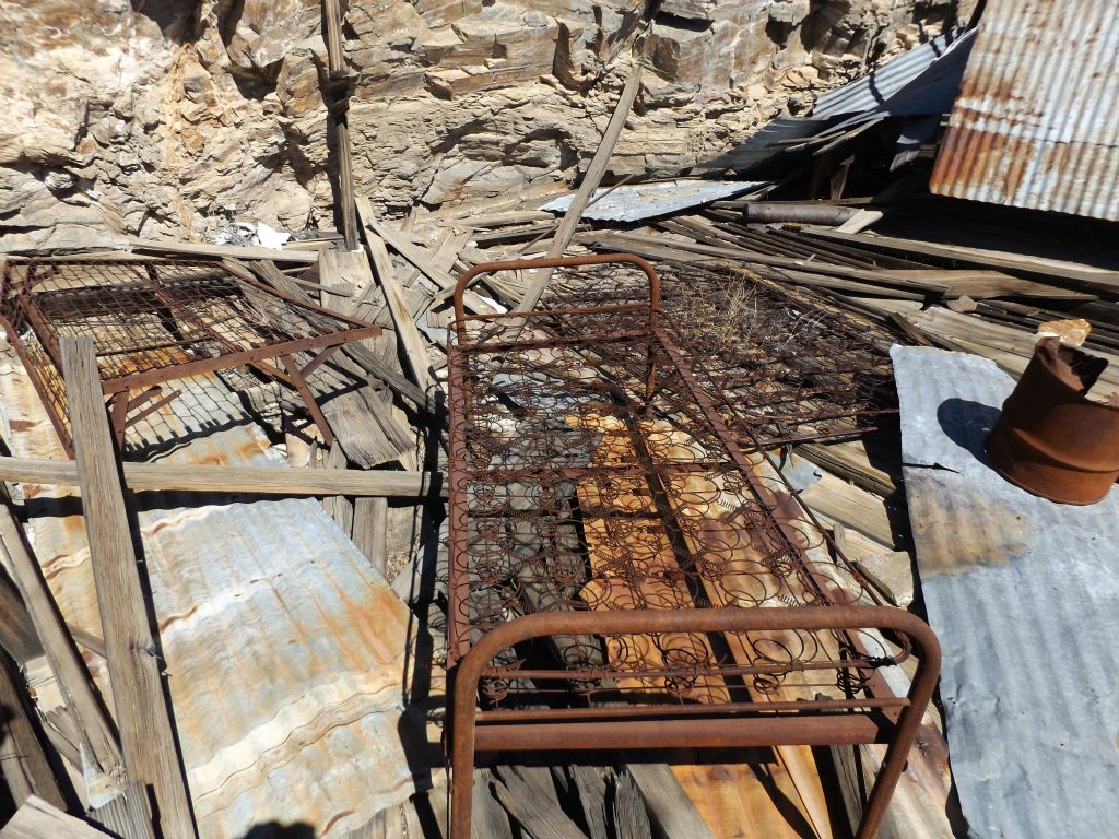 Old rusted beds and mattress springs can be found inside the remains of the shacks: