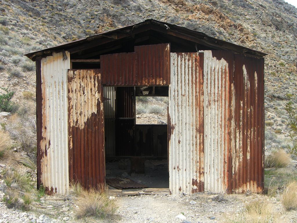 Various pieces of tin siding cover this building except for the areas of missing doors and windows: