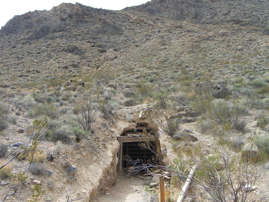 A mining tunnel entrance with a mine heading deep into the hillside: