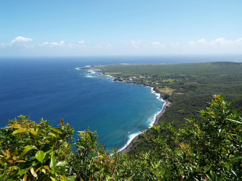 Waves breaking onto the shoreline far below and clouds above the Pacific way in the distance: