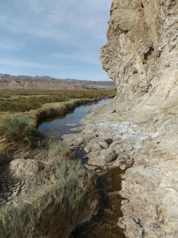 The narrow river weaves between grassy areas on the left and the rock walls on the right: