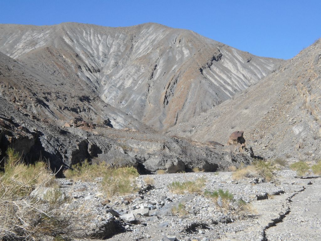 In the distance, there is less solid rock visible above the canyon.  Instead, there are high dirt hillsides: