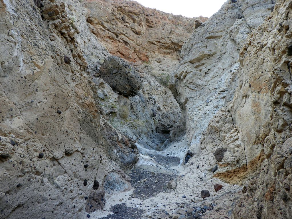 If the dark boulder seen on the left side breaks loose and rolls into the canyon wash, it would create an obstacle to get around: