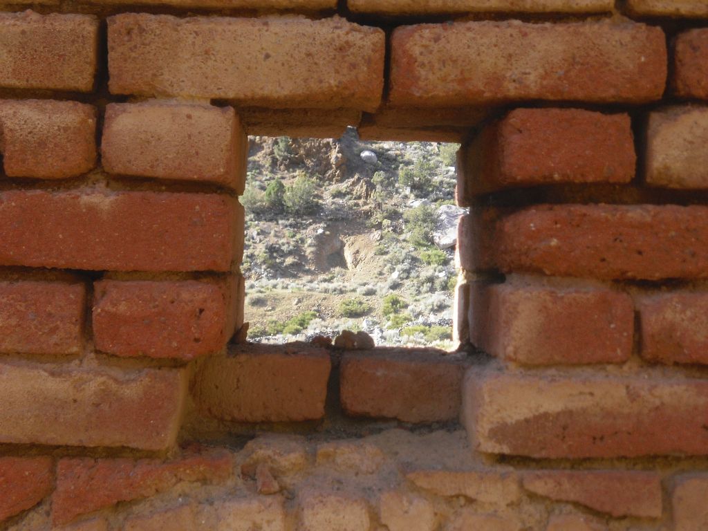 A square opening in the brick arch giving a glimpse of the Panamint terrain:
