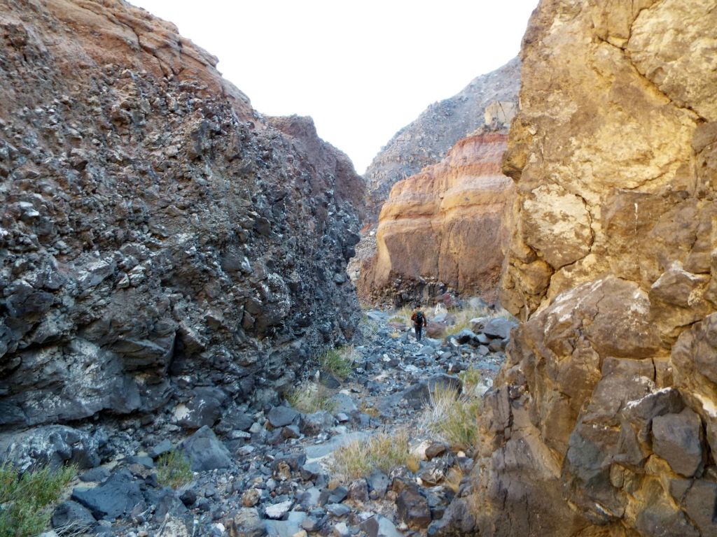 Josh proceeding down canyon in the midst of numerous rock layers and types all around: