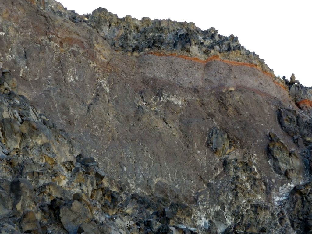A mixture of red and purple smooth rock surrounded by jagged gray rocks: