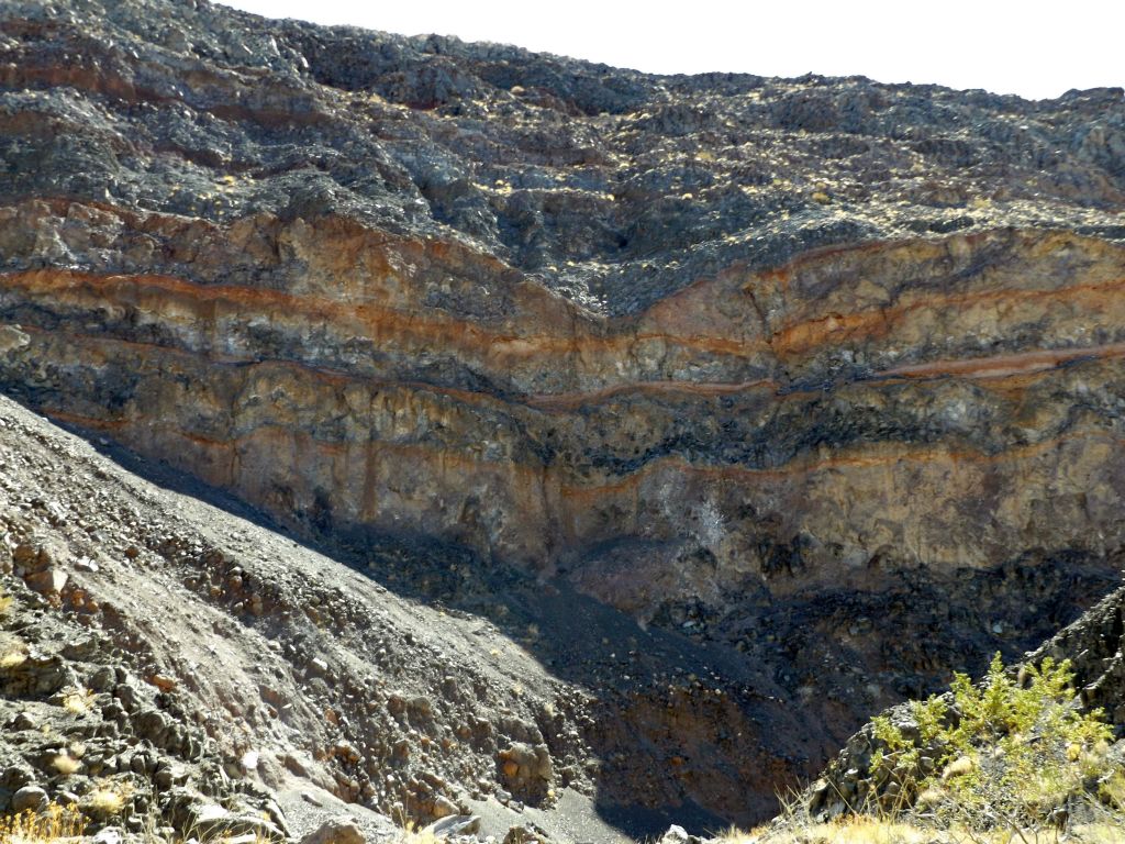 Taking a closer look at the cliff face with color streaks and vertical drop-offs: