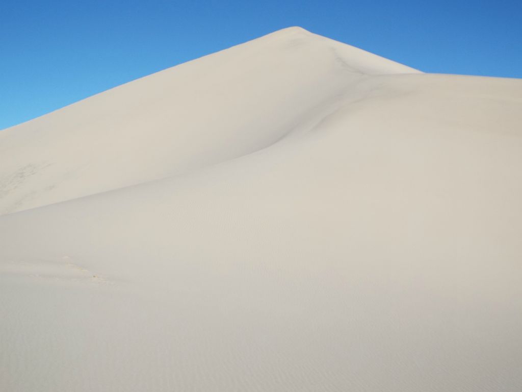 Hiking up pure white sand in order to reach the small peak: